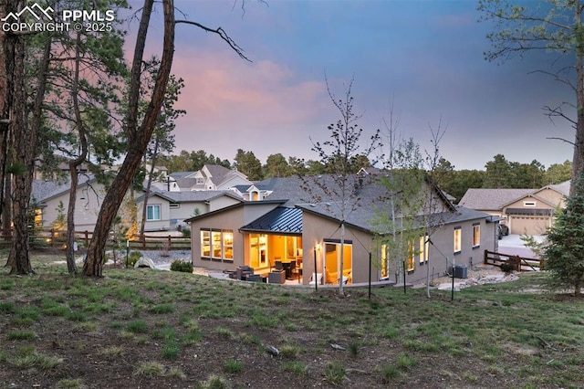 16244 Thunder Cat Way, Monument, CO 80132 - back of house at dusk with a standing seam roof, metal roof, a patio area, and central AC unit