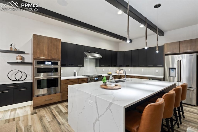 16244 Thunder Cat Way, Monument, CO 80132 - kitchen with premium appliances, open shelves, beam ceiling, light wood-style flooring, and under cabinet range hood