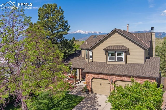 9131 Estebury Cir, Colorado Springs, CO 80920 - view of front facade featuring a mountain view, brick siding, an attached garage, roof with shingles, and driveway