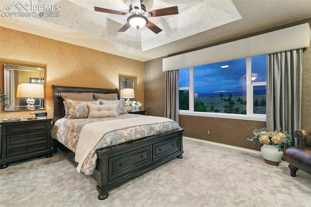 9131 Estebury Cir, Colorado Springs, CO 80920 - bedroom featuring a textured wall, light carpet, a tray ceiling, baseboards, and a ceiling fan