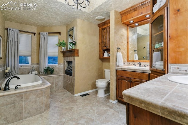 9131 Estebury Cir, Colorado Springs, CO 80920 - bathroom with vanity, toilet, a garden tub, a fireplace, and a textured ceiling