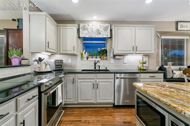 9131 Estebury Cir, Colorado Springs, CO 80920 - kitchen with appliances with stainless steel finishes, a sink, white cabinetry, tasteful backsplash, and recessed lighting