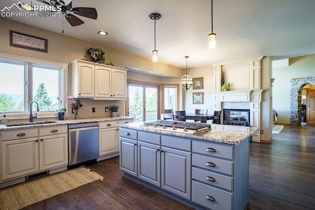 1120 Brenthaven Ct, Monument, CO 80132 - kitchen featuring appliances with stainless steel finishes, a sink, a ceiling fan, a multi sided fireplace, and dark wood finished floors