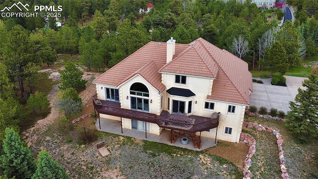 1120 Brenthaven Ct, Monument, CO 80132 - rear view of house featuring a patio area, a tile roof, a chimney, a deck, and stucco siding