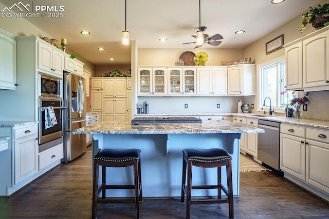 1120 Brenthaven Ct, Monument, CO 80132 - kitchen featuring appliances with stainless steel finishes, a sink, a kitchen bar, a kitchen island, and recessed lighting