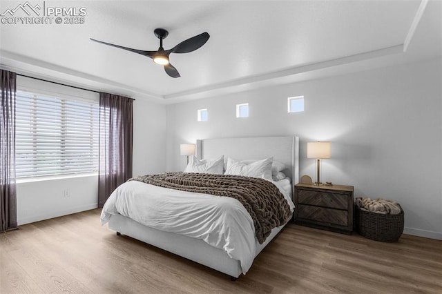 8257 Plumwood Cir, Colorado Springs, CO 80927 - bedroom featuring a raised ceiling, baseboards, wood finished floors, and multiple windows
