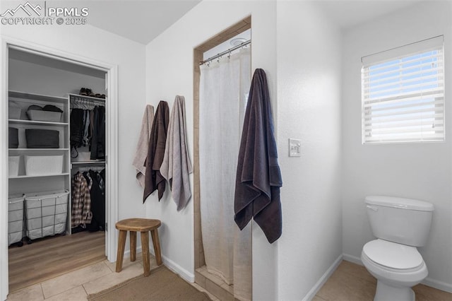 8257 Plumwood Cir, Colorado Springs, CO 80927 - full bathroom featuring tile patterned floors, a shower with shower curtain, a walk in closet, and toilet