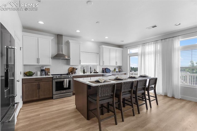 8257 Plumwood Cir, Colorado Springs, CO 80927 - kitchen with wall chimney range hood, stainless steel gas stove, high end refrigerator, a breakfast bar, and light countertops