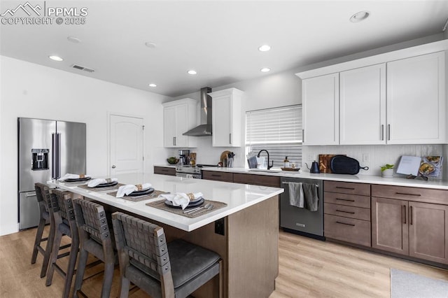 8257 Plumwood Cir, Colorado Springs, CO 80927 - kitchen with stainless steel appliances, wall chimney range hood, a sink, a breakfast bar area, and light countertops