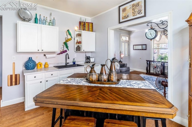 521 W Corona Ave, Pueblo, CO 81004 - kitchen with a sink, ornamental molding, white cabinets, baseboards, and light countertops