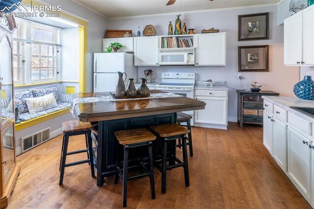 521 W Corona Ave, Pueblo, CO 81004 - kitchen featuring white appliances, white cabinetry, wood finished floors, crown molding, and ceiling fan