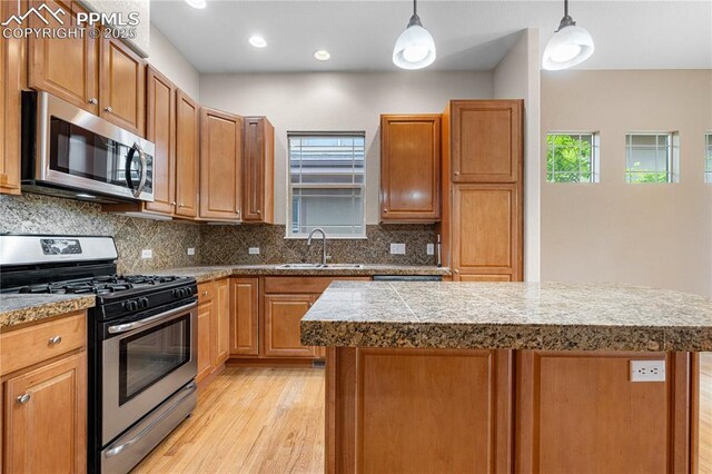 1076 Rosemary St, Denver, CO 80230 - kitchen featuring appliances with stainless steel finishes, light wood-style flooring, a sink, tile counters, and a center island