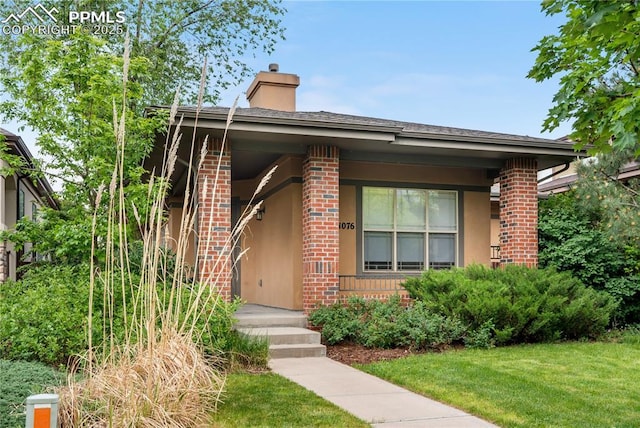 1076 Rosemary St, Denver, CO 80230 - view of front of home with brick siding, a front lawn, a chimney, and stucco siding