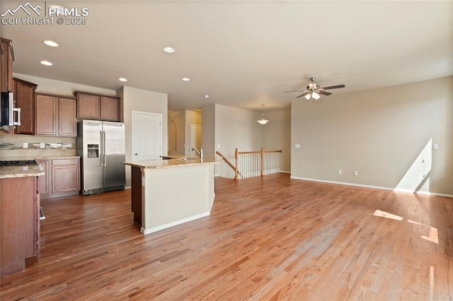 7031 Thorn Brush Way, Colorado Springs, CO 80923 - kitchen with stainless steel appliances, light wood finished floors, a ceiling fan, recessed lighting, and a center island with sink