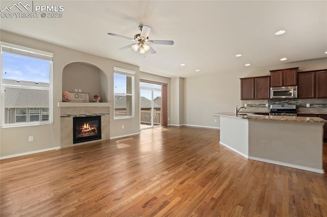 7031 Thorn Brush Way, Colorado Springs, CO 80923 - kitchen with stainless steel appliances, light wood-type flooring, a ceiling fan, a tiled fireplace, and recessed lighting