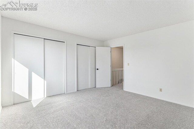 480 W Rockrimmon Blvd Unit D, Colorado Springs, CO 80919 - unfurnished bedroom featuring multiple closets, carpet flooring, and a textured ceiling