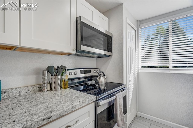111 N 14th St, Colorado Springs, CO 80904 - kitchen with stainless steel appliances, baseboards, a textured wall, white cabinetry, and light stone countertops