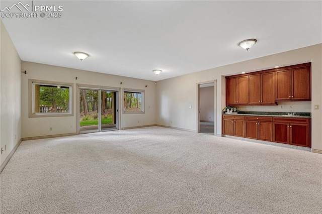 16150 Cliffrock Ct, Colorado Springs, CO 80921 - unfurnished living room featuring a sink, baseboards, and light carpet