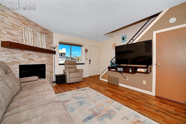 1234 Soaring Eagle Dr, Colorado Springs, CO 80915 - living area featuring wood finished floors, a textured ceiling, stairs, a stone fireplace, and baseboards
