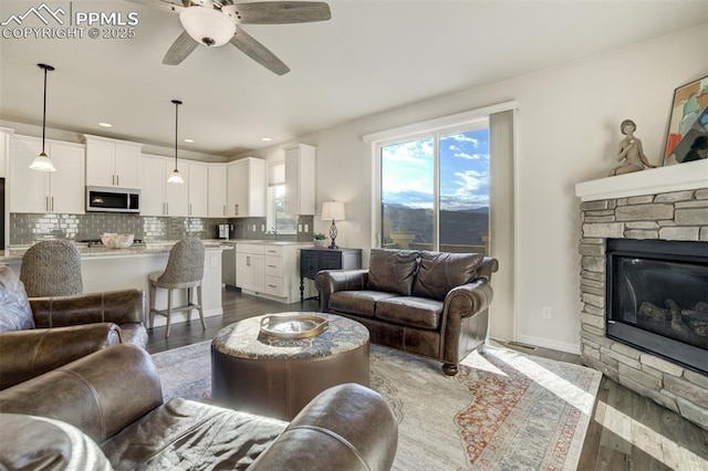 2062 Lone Willow Vw, Colorado Springs, CO 80904 - living area featuring wood finished floors, a ceiling fan, a stone fireplace, a mountain view, and recessed lighting