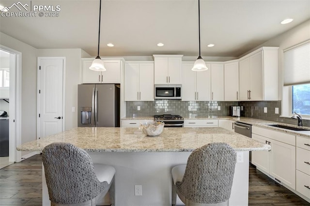 2062 Lone Willow Vw, Colorado Springs, CO 80904 - kitchen with appliances with stainless steel finishes, a sink, white cabinets, a kitchen island, and decorative backsplash