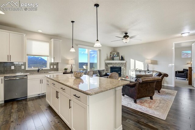 2062 Lone Willow Vw, Colorado Springs, CO 80904 - kitchen featuring dishwasher, a sink, a ceiling fan, a fireplace, and dark wood-style floors