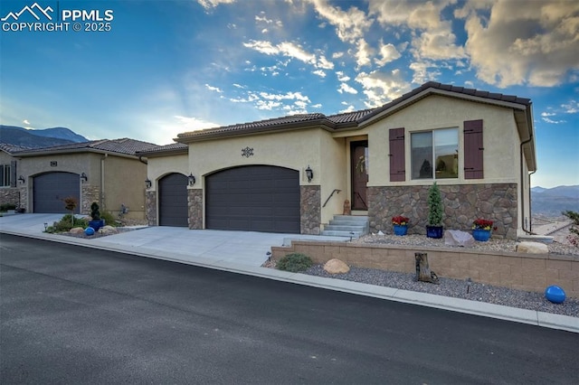 2062 Lone Willow Vw, Colorado Springs, CO 80904 - view of front of home with stone siding, a garage, stucco siding, a mountain view, and concrete driveway