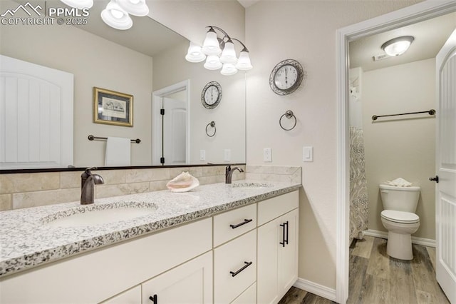 2062 Lone Willow Vw, Colorado Springs, CO 80904 - full bathroom with double vanity, wood finished floors, toilet, and baseboards
