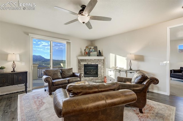 2062 Lone Willow Vw, Colorado Springs, CO 80904 - living area featuring a ceiling fan, wood finished floors, baseboards, and a stone fireplace