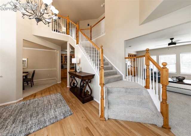 12515 Broad Oaks Dr, Colorado Springs, CO 80921 - stairway featuring wood finished floors, baseboards, a chandelier, a ceiling fan, and a towering ceiling