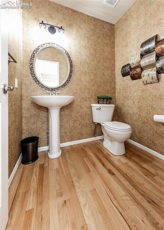 12515 Broad Oaks Dr, Colorado Springs, CO 80921 - bathroom with wood finished floors, toilet, and wallpapered walls