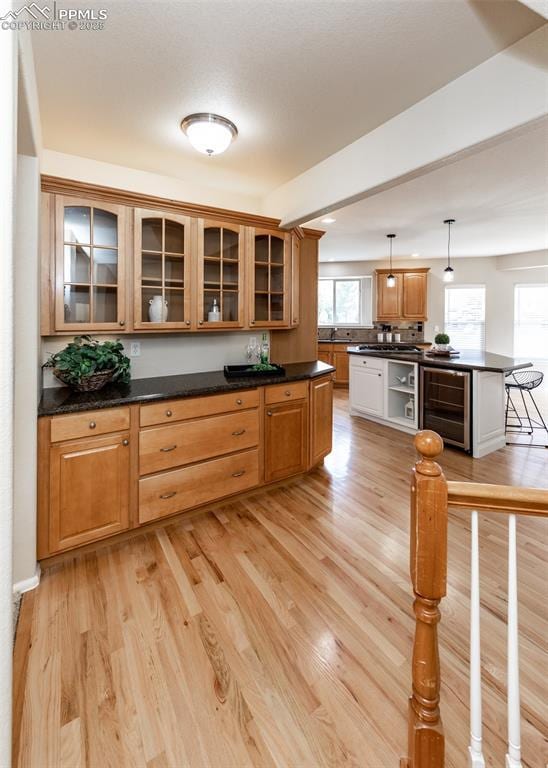 12515 Broad Oaks Dr, Colorado Springs, CO 80921 - kitchen featuring wine cooler, dark countertops, light wood finished floors, and pendant lighting