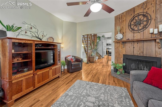 115 N 24th St, Colorado Springs, CO 80904 - living area with ceiling fan, light wood-type flooring, a fireplace with raised hearth, and wooden walls