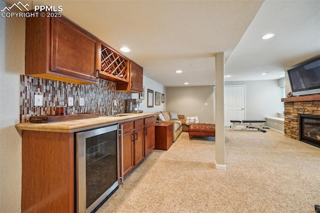 8445 Jacks Fork Dr, Colorado Springs, CO 80924 - indoor wet bar with wine cooler, light carpet, recessed lighting, a stone fireplace, and backsplash