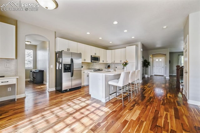 8445 Jacks Fork Dr, Colorado Springs, CO 80924 - kitchen with appliances with stainless steel finishes, arched walkways, wood finished floors, tasteful backsplash, and recessed lighting