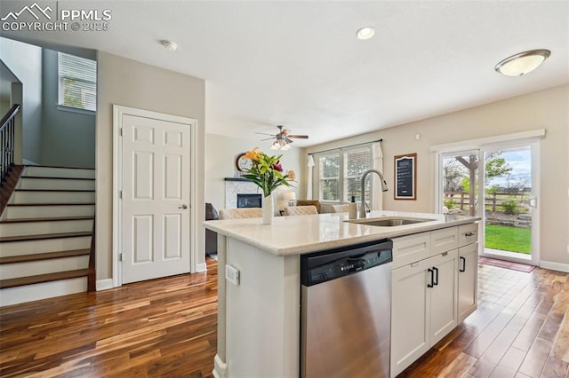 8445 Jacks Fork Dr, Colorado Springs, CO 80924 - kitchen featuring stainless steel dishwasher, a glass covered fireplace, a sink, dark wood-style floors, and recessed lighting