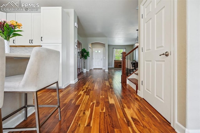 8445 Jacks Fork Dr, Colorado Springs, CO 80924 - foyer entrance with arched walkways, dark wood-style floors, stairs, and baseboards