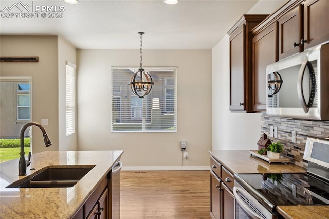 7663 Double Barrel Hts, Colorado Springs, CO 80923 - kitchen with stainless steel appliances, a sink, tasteful backsplash, hanging light fixtures, and a chandelier