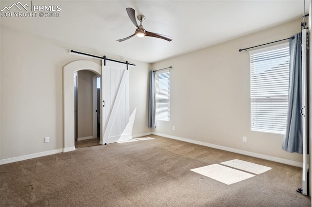 7663 Double Barrel Hts, Colorado Springs, CO 80923 - carpeted spare room with a barn door, a ceiling fan, arched walkways, and baseboards