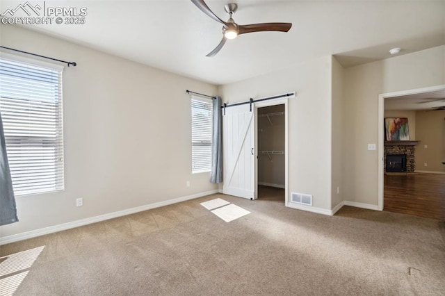 7663 Double Barrel Hts, Colorado Springs, CO 80923 - unfurnished bedroom with carpet, a fireplace, baseboards, a walk in closet, and a ceiling fan