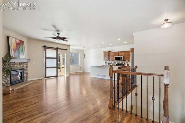 7663 Double Barrel Hts, Colorado Springs, CO 80923 - living room with a barn door, wood finished floors, a fireplace, a ceiling fan, and recessed lighting