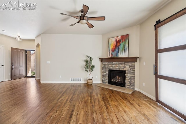 7663 Double Barrel Hts, Colorado Springs, CO 80923 - unfurnished living room featuring wood finished floors, a ceiling fan, a stone fireplace, and baseboards