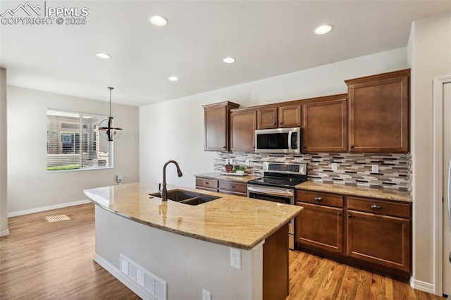 7663 Double Barrel Hts, Colorado Springs, CO 80923 - kitchen with stainless steel appliances, a sink, decorative backsplash, light wood-type flooring, and light stone counters
