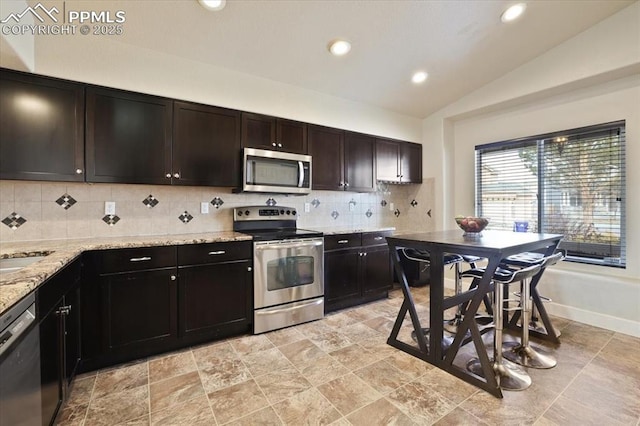 7719 Paca Pl, Fountain, CO 80817 - kitchen with stainless steel appliances, vaulted ceiling, backsplash, recessed lighting, and light stone countertops