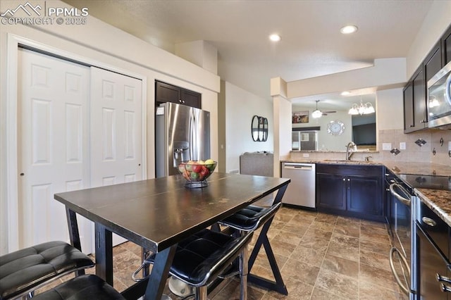 7719 Paca Pl, Fountain, CO 80817 - kitchen featuring stainless steel appliances, a sink, tasteful backsplash, recessed lighting, and light stone finish flooring