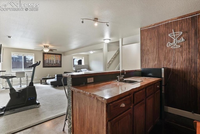 7719 Paca Pl, Fountain, CO 80817 - kitchen featuring a sink, open floor plan, ceiling fan, a textured ceiling, and a breakfast bar area