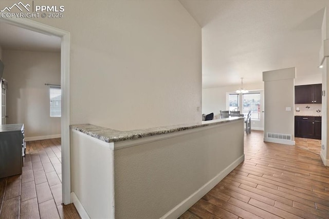 7719 Paca Pl, Fountain, CO 80817 - hallway with wood finished floors, a chandelier, lofted ceiling, and baseboards