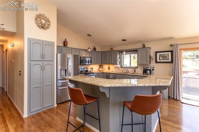 1053 Kings Crown Rd, Woodland Park, CO 80863 - kitchen with appliances with stainless steel finishes, gray cabinetry, a kitchen bar, light wood-style flooring, and backsplash
