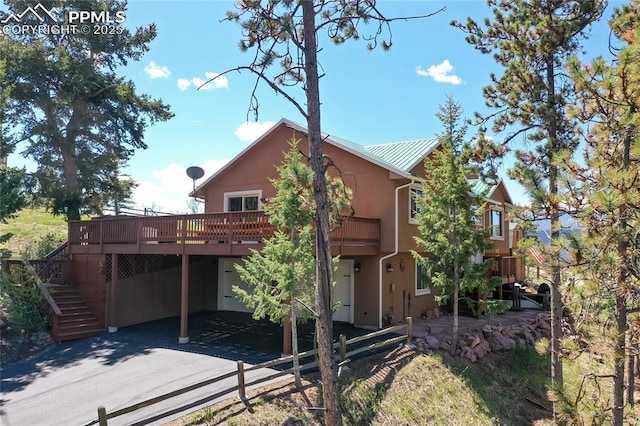 1053 Kings Crown Rd, Woodland Park, CO 80863 - back of property featuring a deck, stairway, stucco siding, a carport, and metal roof