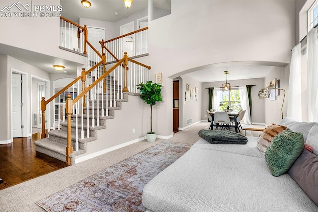9883 Red Sage Dr, Colorado Springs, CO 80920 - living room with arched walkways, a towering ceiling, baseboards, stairway, and carpet floors